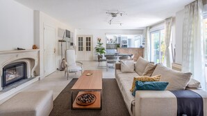 A modern living room with a fireplace, a sofa, a coffee table, and a dining area.