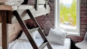 Een stapelbed met een houten ladder, witte beddengoed en een raam met uitzicht op bomen.