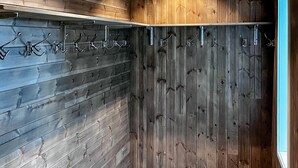 Een hoek van een kamer met een houten wand en een metalen rek met haken.