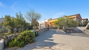 A paved courtyard with a stone wall, a metal gate, and a small garden area with shrubs and a tree. - Gorgeous apartment in Pirovac with WiFi (Pirovac)