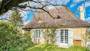 A stone house with a sloped roof, wooden shutters, and a small front porch.