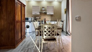 A compact kitchen with a wooden cabinet, a washing machine, and a dining area with a white lattice table and chairs. - Beautiful home in Nettuno with WiFi (Nettuno)
