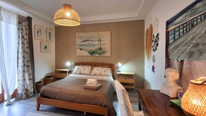 A bedroom with a wooden bed, two bedside tables with lamps, a painting on the wall, and a decorative head sculpture. - Beautiful home in Nettuno with WiFi (Nettuno)