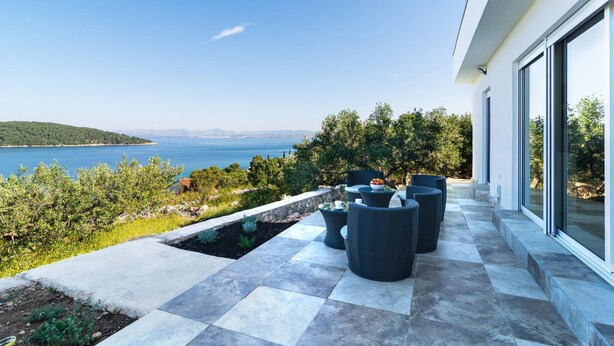 A terrace with outdoor furniture, a view of the sea, and a stone wall.