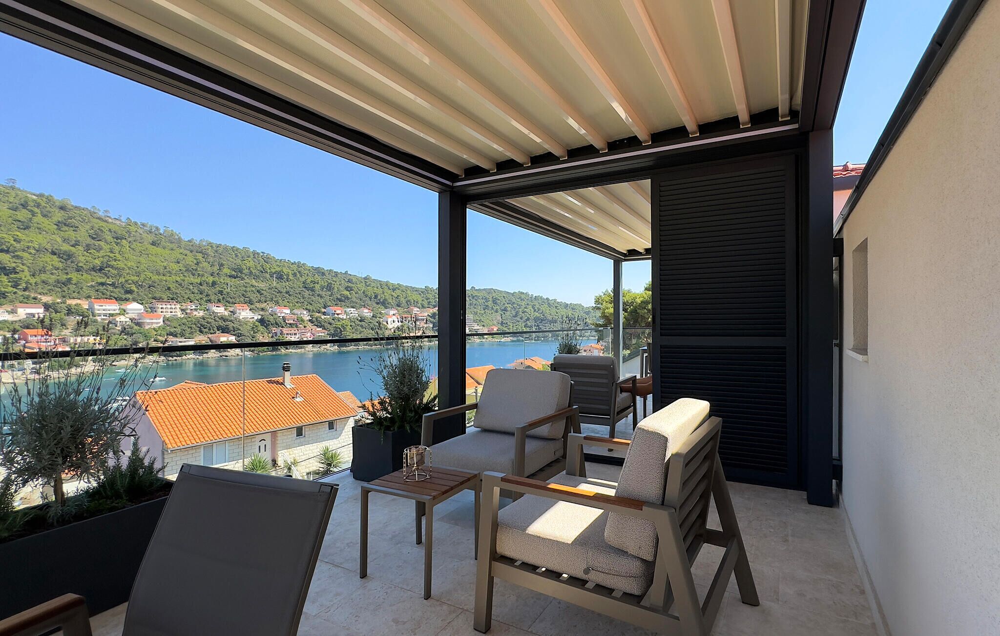 Ein Balkon mit Blick auf einen Fluss und Häuser, ausgestattet mit Stühlen und einem Tisch.