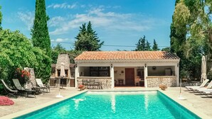 Una villa junto a la piscina con fachada de piedra y techo de tejas.