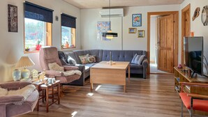 A cozy living room with a grey sofa, a wooden coffee table, and a TV on a wooden stand. - Stunning home in Farsø with WiFi (Farsø)