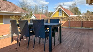 A wooden deck with a table and chairs, surrounded by a wooden fence and houses in the background. - Stunning home in Farsø with WiFi (Farsø)