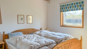 A bedroom with a wooden bed, two framed pictures on the wall, and a window with a patterned valance. - Stunning home in Farsø with WiFi (Farsø)