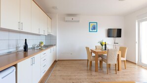 A modern kitchen with white cabinets, a wooden countertop, and a dining area with a table and chairs. - Beautiful apartment in Duce with house sea view (Duce)