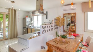 A modern kitchen with a built-in oven, a dining area with a wooden table, and a decorative mirror. - Beautiful home in Grospierres (Grospierres)