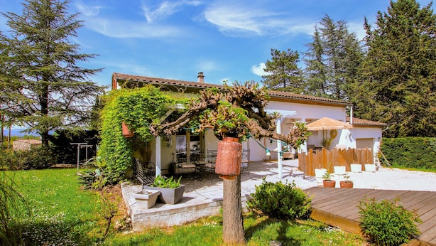 A house with a garden, a pergola covered with vines, and a wooden deck. - Beautiful home in Grospierres (Grospierres)