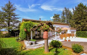 Ein Haus mit Garten, einer mit Wein bewachsenen Pergola und einer Holzterrasse.