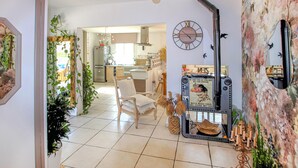 A modern kitchen with a refrigerator, a dining area with a chair, and a wall clock. - Beautiful home in Grospierres (Grospierres)