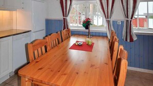A wooden dining table with chairs, a red placemat, and a vase with flowers. - Nice apartment in Sälen with sauna (Sälen)