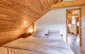 Relax in this serene bedroom with a large bed and cozy nightstand, set amidst a rustic natural setting.