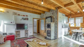Un amplio salón con pared de piedra, techo de madera y televisor.