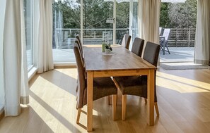 En matplats med ett träbord och stolar, stora fönster och utsikt över omgivningen.