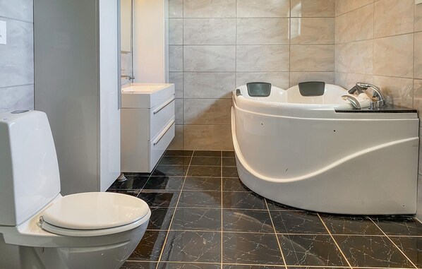 Une salle de bain moderne équipée de toilettes, d’un lavabo et d’une baignoire.