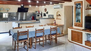 A compact kitchen with a dining area, featuring a wooden table and chairs, a built-in oven, and a microwave.