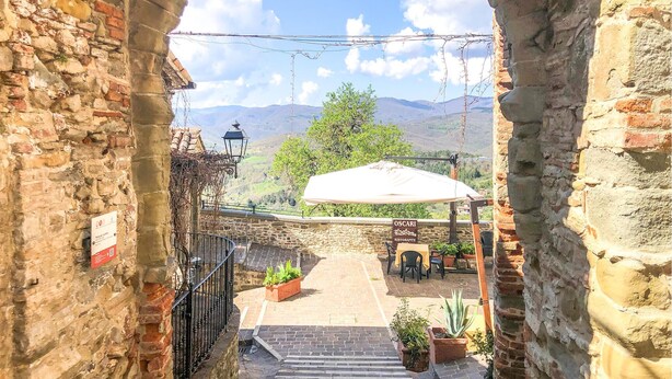 A stone-walled courtyard with a restaurant named "OSCARI" and a view of green hills in the background. - Pet friendly apartment (Monte S.Maria Tiberina)