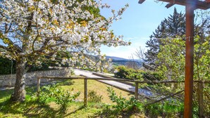 A garden with a stone wall, a wooden pergola, and a view of a road and distant hills. - Pet friendly apartment (Monte S.Maria Tiberina)