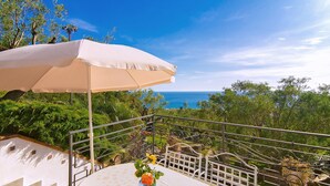 A balcony with a table, an umbrella, and a view of the ocean.