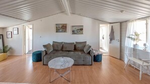 A spacious living area with a grey sofa, a small round table, and a potted plant. - Beautiful home in Höör with WiFi (Höör)