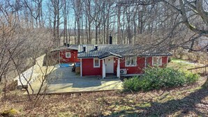 A small red cabin with a tiled roof, surrounded by trees and a wooden deck. - Beautiful home in Höör with WiFi (Höör)