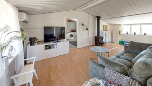 A spacious living area with a sofa, a TV, a kitchen with a stove, and a washing machine. - Beautiful home in Höör with WiFi (Höör)