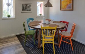 A dining area with a round table, colorful chairs, a hanging pendant light, and artwork on the walls. - Beautiful home in Höör with WiFi (Höör)