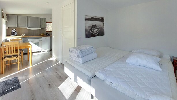 A bedroom with a bed, a desk, and a kitchenette in the background. - Beautiful home in Höör with WiFi (Höör)