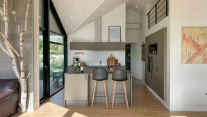 A modern kitchen with a central island, two bar stools, and a large window. - 3 bedroom amazing home in Nexø (Nexø)