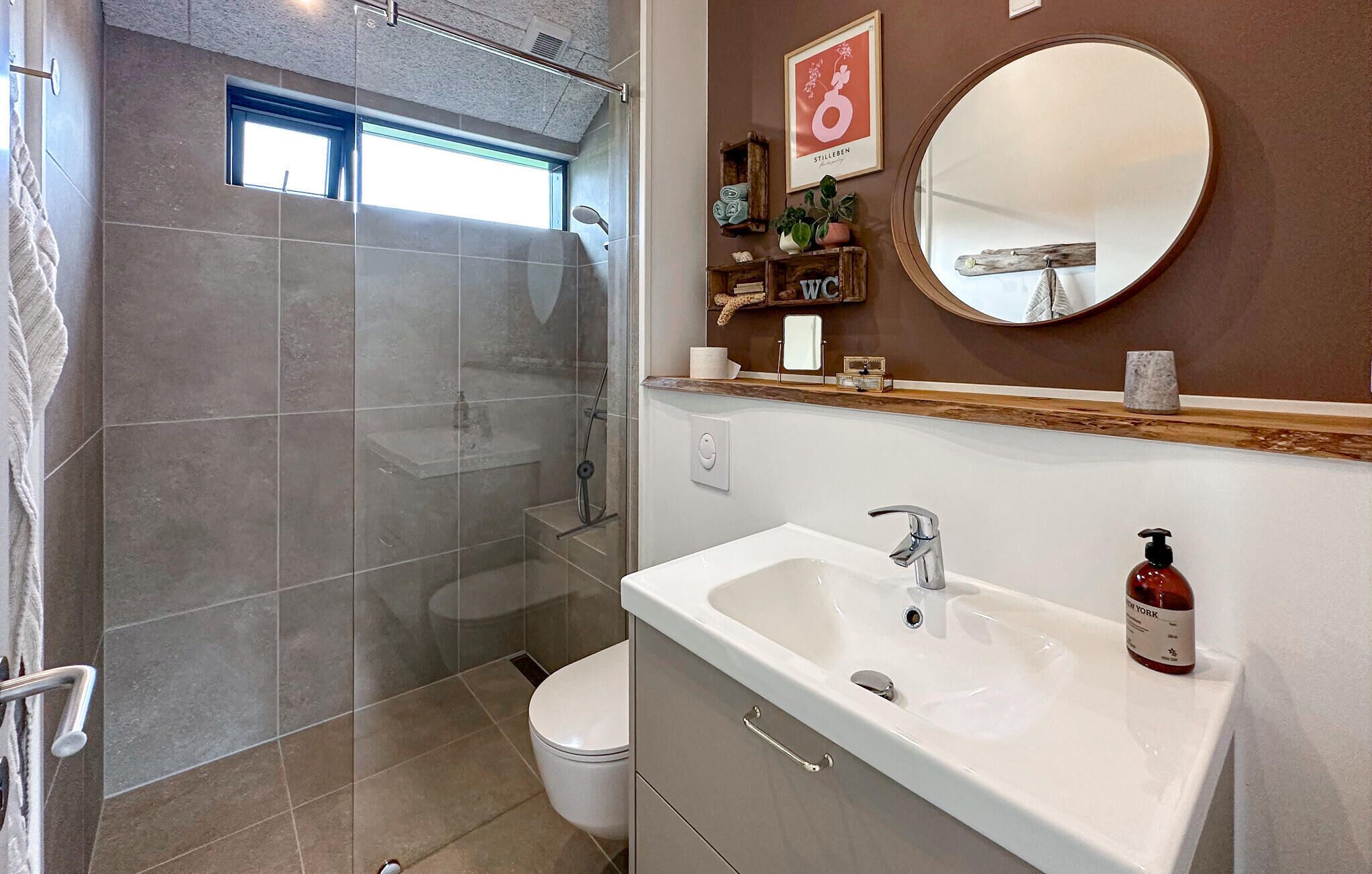 A bathroom with a shower, toilet, sink, and a mirror.