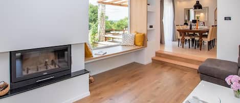 Una sala de estar moderna con chimenea, un comedor con mesa y sillas, y vistas al exterior.