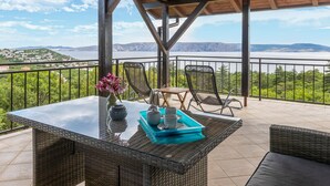 A covered outdoor seating area with a table, chairs, and a view of a lake and mountains. - Cozy apartment in Klenovica with WiFi (Klenovica)