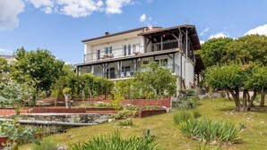 A two-story house with a balcony, surrounded by greenery and a stone retaining wall. - Cozy apartment in Klenovica with WiFi (Klenovica)