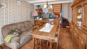 Una sala de estar acogedora con sofá, mesa de comedor de madera y zona de cocina con armarios de madera y una escalera.