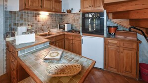 Una cocina con armarios de madera, microondas, estufa y refrigerador.