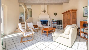 A living room with a fireplace, white sofas, wooden chairs, a coffee table, and a bookshelf. - Gorgeous home in Saint Aygulf (Saint Aygulf)