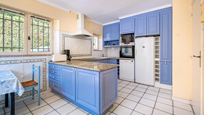 A kitchen with blue cabinets, a white refrigerator, and a window with a view of greenery. - Gorgeous home in Saint Aygulf (Saint Aygulf)