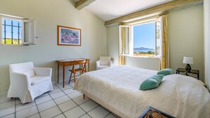 A bedroom with a bed, a chair, a small table, a lamp, and a painting on the wall. - Gorgeous home in Saint Aygulf (Saint Aygulf)
