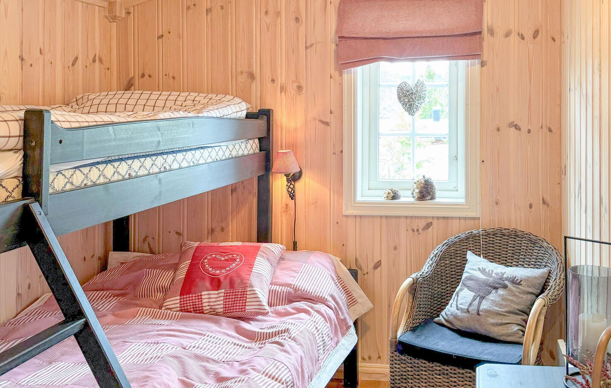 Een gezellige kamer met een stapelbed, een rieten stoel, een klein tafeltje en een raam met uitzicht op de omgeving.