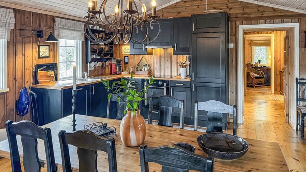A modern kitchen with dark cabinetry, a central island, and a chandelier. - Cozy home in Nissedal with sauna (Nissedal)