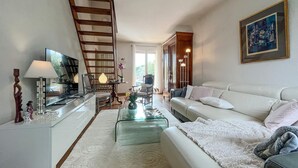 A modern living room with a sofa, coffee table, and a TV. There is a staircase leading to another level. - Gorgeous home in Roquemaure (Roquemaure)