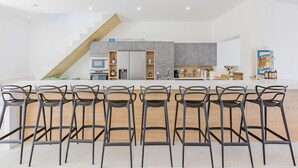 Une cuisine moderne dotée d’un îlot central, d’un escalier et d’un coin repas avec des chaises.