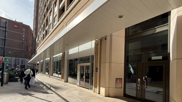 A building with a glass entrance, a sign for 'ibis,' and a pedestrian walkway. -  2-bedroom apartment near Canning Town Station E16 1GW London (London)
