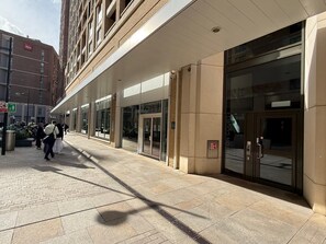 Un edificio con entrada de vidrio, un letrero que dice 'ibis' y una acera.