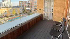 A balcony with a wooden ceiling, a glass door, and two black chairs. -  2-bedroom apartment near Canning Town Station E16 1GW London (London)