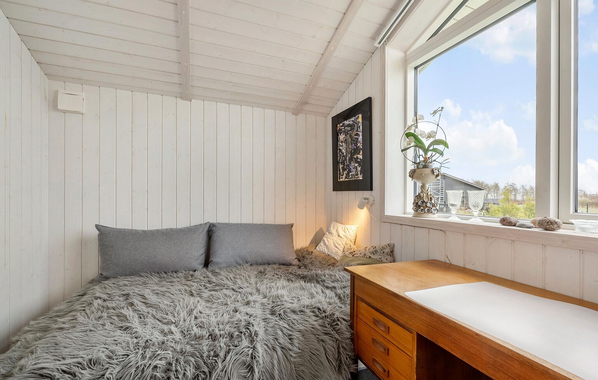 Ein Schlafzimmer mit einem Bett, einer Holzkommode, einem Fenster mit Blick und einer Wand-Klimaanlage.